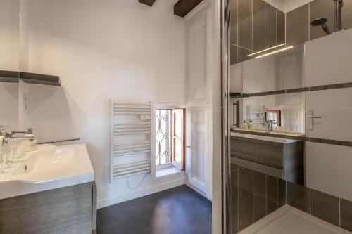 a white bathroom with a sink and a window at Logis de la Prévôté in Saint-Aignan