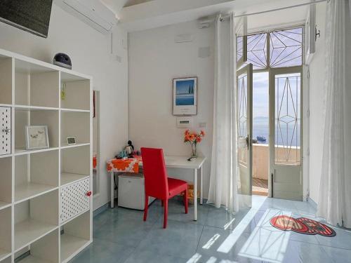 a red chair sitting at a desk in a room with a window at Amalfi Rooms Duoglio Beach -amazing seaview in Amalfi