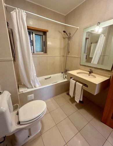 a bathroom with a toilet and a sink and a tub at Apartamentos Santa Teresinha in Alvor