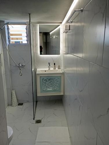 a white bathroom with a sink and a mirror at Katerina's Apartment in Ancient Epidauros