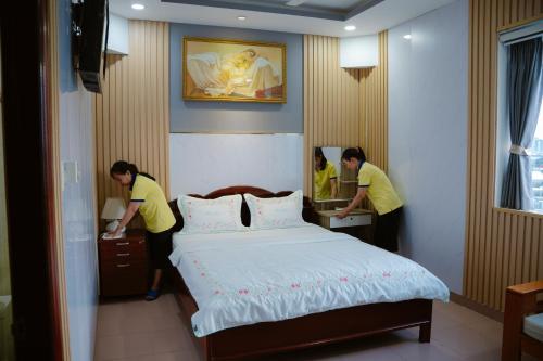 two women standing next to a bed in a room at Hoàng Sơn Hotel in Ho Chi Minh City