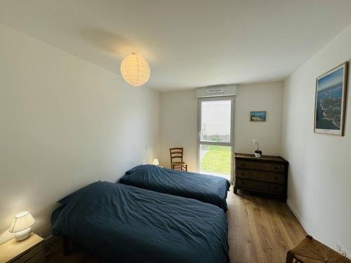 une chambre avec deux lits et un bureau et une fenêtre dans l'établissement 3 pièces 68m², jardin clos, 150m plage, wifi, à Saint-Pierre-Quiberon