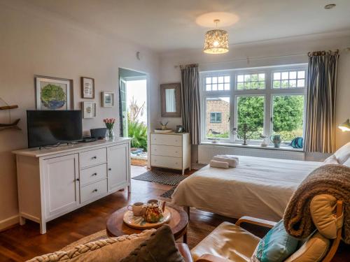 a bedroom with a bed and a tv and a couch at The Apartment at Queen Anne's Lodge in Lyme Regis