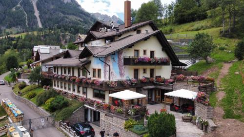 a house in the mountains with flowers on it at Hotel El Laresh in Moena