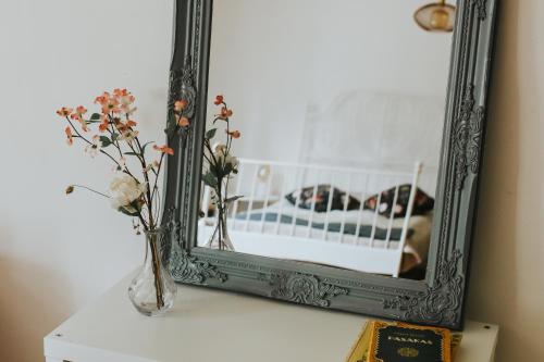 a mirror on a table with flowers in a vase at Ķimales muiža in Ķimale