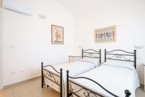 two beds in a room with white walls at Agriturismo La Genziana in Alghero