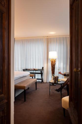 a hotel room with a bed and a couch and a table at Villa Carona Hotel & Spa in Carona