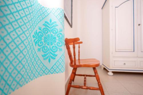 a wooden chair next to a wall with a quilt at Agriturismo La Genziana in Alghero