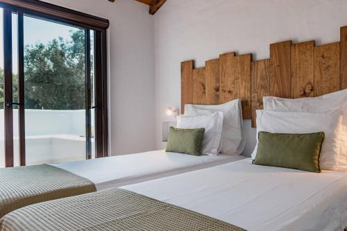 two beds in a bedroom with a large window at Monte do Serrado De Baixo in Évora