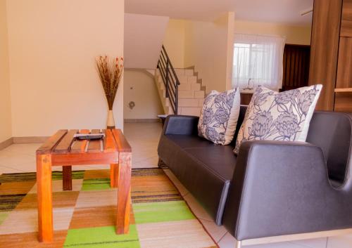 a living room with a black couch and a table at Hotel Prestige Ongwediva in Ongwediva