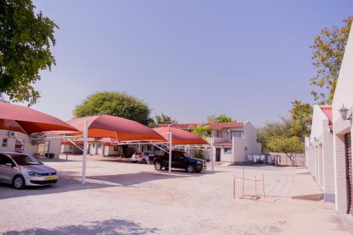 a group of red umbrellas in a parking lot at Hotel Prestige Ongwediva in Ongwediva
