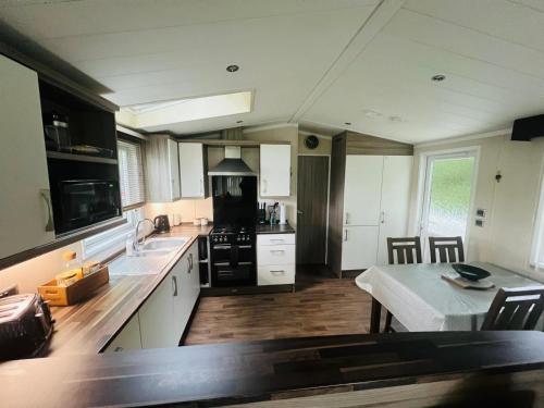 a kitchen with white cabinets and a table with a tableablish at Marigold lodge 8 at Oakdene Forest Park in Saint Leonards