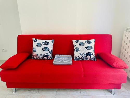 a red couch with three pillows on top of it at Casa ORI in Montesilvano