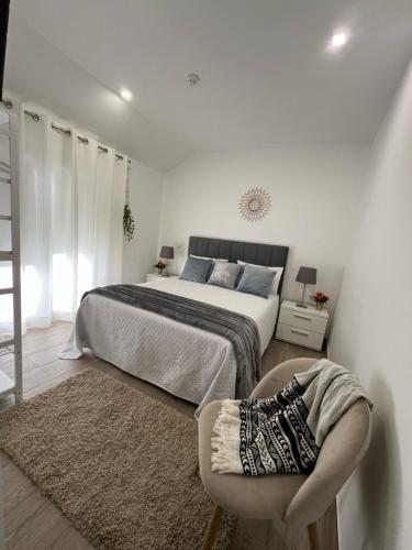 a white bedroom with a bed and a chair at Old Dream in Nazaré