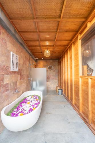 a bathroom with a large tub with flowers in it at The Patra Villa Sebatu by Dhananjaya Hospitality in Tampaksiring