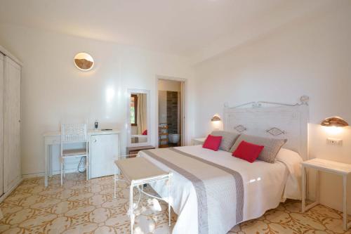 a white bedroom with a large bed with red pillows at Agriturismo La Genziana in Alghero