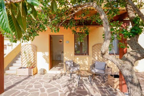 a patio with chairs and a table and a tree at Agriturismo La Genziana in Alghero