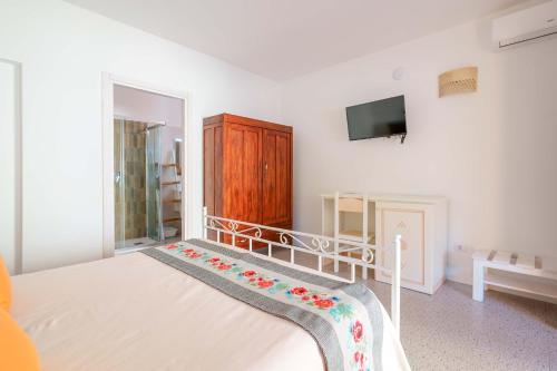 a bedroom with a bed and a tv on the wall at Agriturismo La Genziana in Alghero