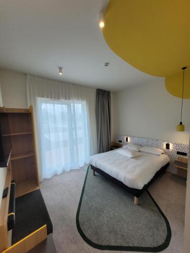 a bedroom with a bed and a large window at Hôtel AKENA Strasbourg - Hoerdt in Hoerdt