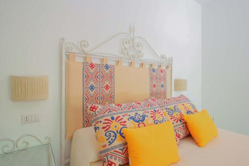 a bedroom with a bed with colorful pillows at Agriturismo La Genziana in Alghero
