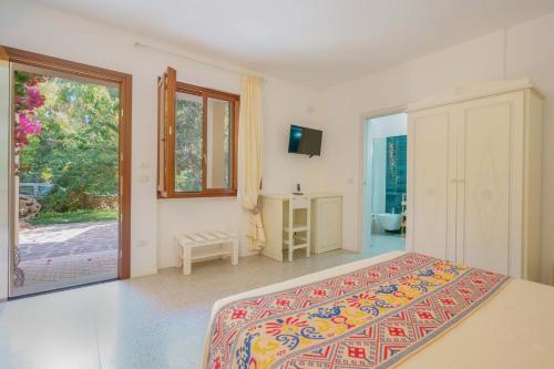 a bedroom with a bed and a tv and a window at Agriturismo La Genziana in Alghero