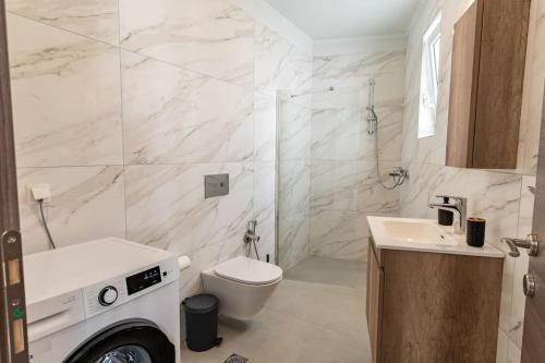 a white bathroom with a toilet and a sink at Armonia Suite in Panormos Rethymno