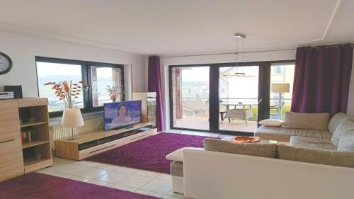 a living room with a couch and a tv at Ferienwohnung Seeblick II in Schalkenmehren