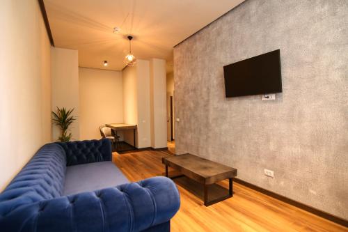 a living room with a blue couch and a tv on a wall at Casa Iacob ApartHotel in Braşov