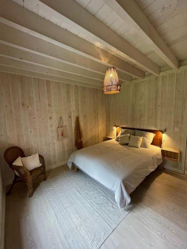 une chambre avec un grand lit et un lustre dans l'établissement La maison dans la carrière, à Regnéville-sur-Mer