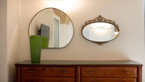 a mirror on a wall above a dresser with a green vase at Chicca's Rooms in Lecce