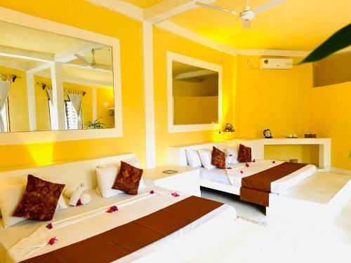 two beds in a room with yellow walls and mirrors at Dream Luxury B&b Watamu in Watamu