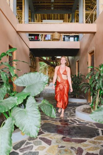 a woman walking through a building with plants at The Journey Hostel in Los Naranjos