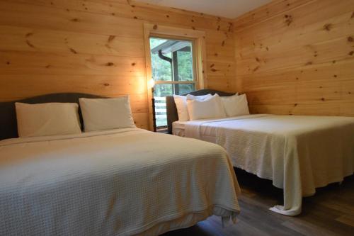 two beds in a room with wooden walls at Goss at Lake Lure in Lake Lure