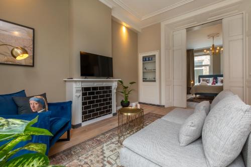 a living room with a blue couch and a fireplace at Het Herenhuis Middelburg in Middelburg
