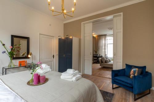 a bedroom with a bed and a blue chair at Het Herenhuis Middelburg in Middelburg