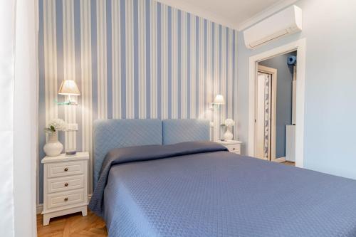 a bedroom with a blue bed and striped walls at H11 CASA CAMILLA Centro - Sanremo in Sanremo