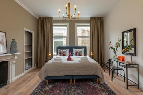 a bedroom with a blue bed and a fireplace at Het Herenhuis Middelburg in Middelburg