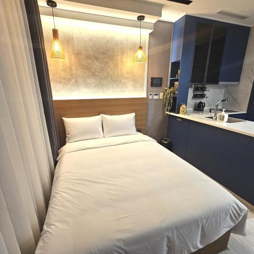 a bedroom with a white bed and a kitchen at 라비앙즈-Raviens-Elliy's Room in Busan