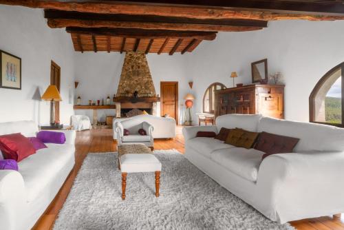 a living room with white couches and a fireplace at Can Serola in Sales del Llierca