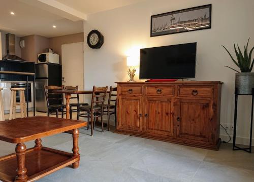 un salon avec une télévision sur un meuble en bois dans l'établissement Proche Lorient Location meublée confortable pour 2 personnes, à Cléguer