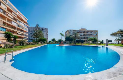 Una gran piscina azul con edificios al fondo. en Colina del Mar, en Torremolinos