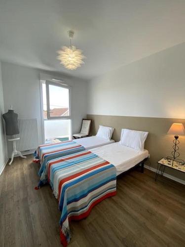 une chambre avec deux lits avec une couverture rayée dessus dans l'établissement Appartement Méréa, à Arès