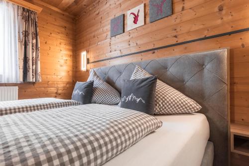 two beds in a room with wooden walls at Apart Schneider in Ischgl