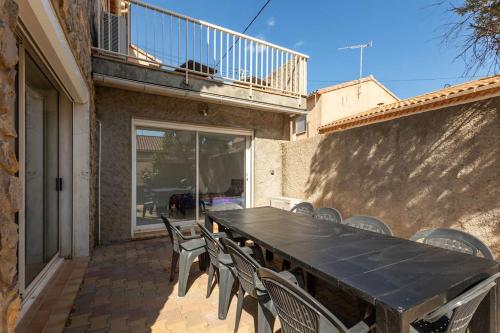 une grande table et des chaises noires sur la terrasse dans l'établissement Villa Familiale Gaming - 4 chambres, à Valras-Plage