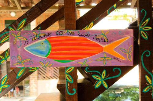 a wooden sign with a fish painted on it at Pousada Maracaju in Porto De Galinhas