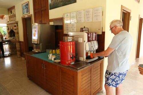 een man staat bij een toonbank met een koffiezetapparaat bij Mavruka Hotel in Oludeniz