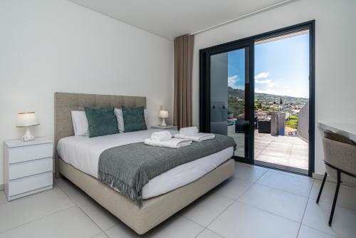 a bedroom with a bed with a view of a balcony at Casa Antonette, Lovely house with a pool in Calheta