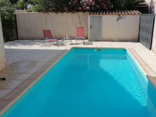 une piscine avec deux chaises et une table dans l'établissement La Maison de Joséphine 4 chambres, à Pierrelatte