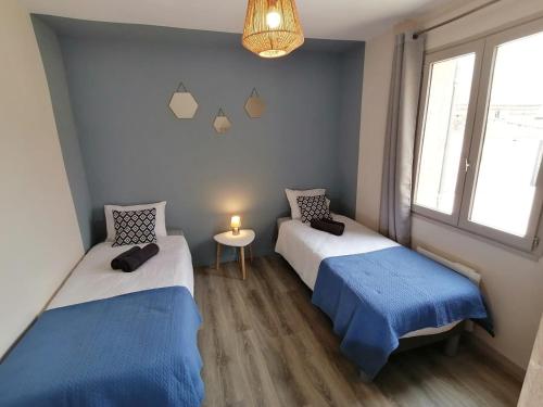 a room with two beds and a table and a window at La Maison de Joséphine 4 chambres in Pierrelatte
