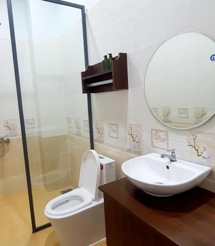 a bathroom with a sink and a toilet and a mirror at Nhà nghỉ Rico in Rạch Giá